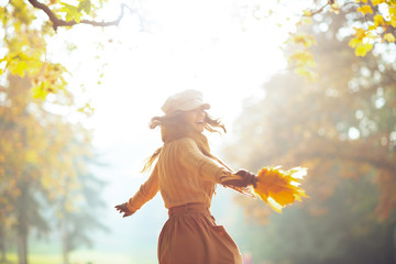 woman with yellow leaves having fun time outside in autumn park