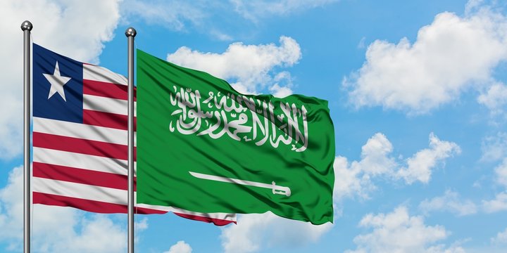 Liberia and Saudi Arabia flag waving in the wind against white cloudy blue sky together. Diplomacy concept, international relations.
