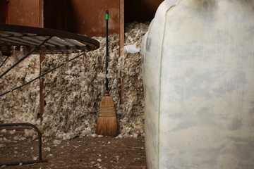 piles of freshly shorn wool swept into bays waiting to be bagged into bales for selling on a small family farm in rural Victoria, Australia