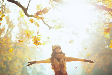 happy woman enjoying autumn and catching falling yellow leaves