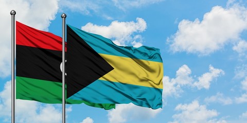 Libya and Bahamas flag waving in the wind against white cloudy blue sky together. Diplomacy...