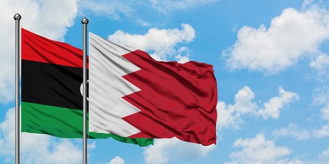 Libya and Bahrain flag waving in the wind against white cloudy blue sky together. Diplomacy concept, international relations.