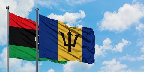 Libya and Barbados flag waving in the wind against white cloudy blue sky together. Diplomacy concept, international relations.