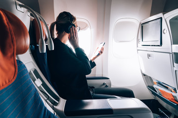 Female passenger in headphones  listening audio book on board during intercontinental flight.Young...