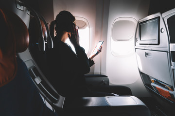 Successful female lawyer making intercontinental flight in first class listening music via...
