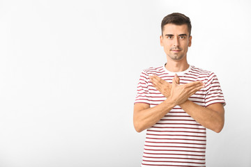 Young deaf mute man using sign language on white background