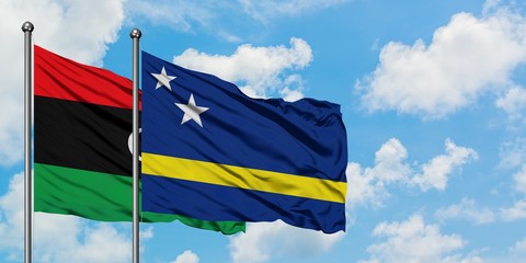 Libya and Curacao flag waving in the wind against white cloudy blue sky together. Diplomacy concept, international relations.