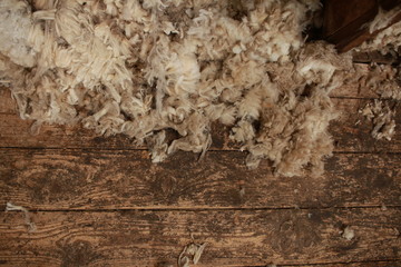 piles of freshly shorn wool scattered on the timber floor of the family farm woolshed shearing shed, rural Victoria, Australia
