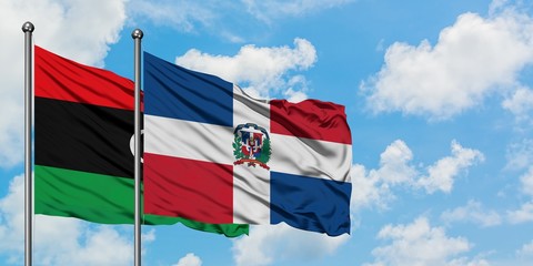 Libya and Dominican Republic flag waving in the wind against white cloudy blue sky together....
