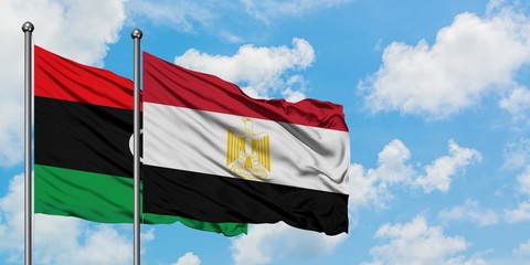 Libya and Egypt flag waving in the wind against white cloudy blue sky together. Diplomacy concept, international relations.