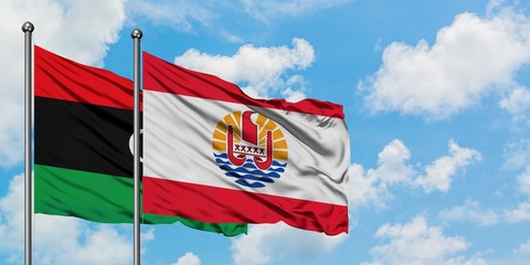 Libya and French Polynesia flag waving in the wind against white cloudy blue sky together....