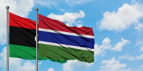 Libya and Gambia flag waving in the wind against white cloudy blue sky together. Diplomacy concept, international relations.