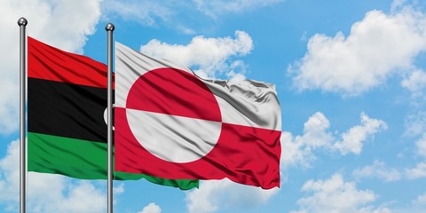 Libya and Greenland flag waving in the wind against white cloudy blue sky together. Diplomacy concept, international relations.