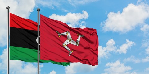 Libya and Isle Of Man flag waving in the wind against white cloudy blue sky together. Diplomacy concept, international relations.