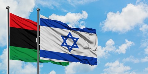 Libya and Israel flag waving in the wind against white cloudy blue sky together. Diplomacy concept, international relations.