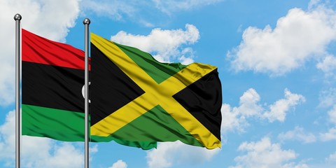 Libya and Jamaica flag waving in the wind against white cloudy blue sky together. Diplomacy concept, international relations.
