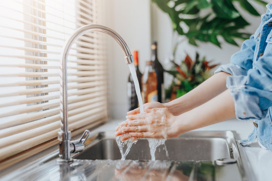 Woman washing hands in sink before cooking in kitchen