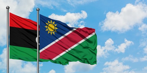 Libya and Namibia flag waving in the wind against white cloudy blue sky together. Diplomacy...