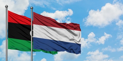 Libya and Netherlands flag waving in the wind against white cloudy blue sky together. Diplomacy concept, international relations.