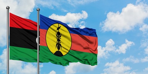 Libya and New Caledonia flag waving in the wind against white cloudy blue sky together. Diplomacy...