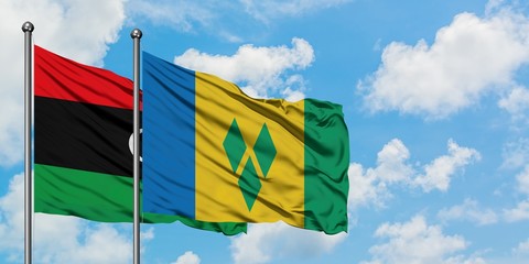 Libya and Saint Vincent And The Grenadines flag waving in the wind against white cloudy blue sky together. Diplomacy concept, international relations.