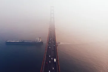 Photo sur Plexiglas Pont du Golden Gate Aerial view of Golden Gate Bridge in foggy visibility during evening time, metropolitan transportation  infrastructure, birds eye view of automotive car vehicles on road of suspension construction