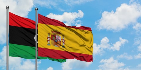 Libya and Spain flag waving in the wind against white cloudy blue sky together. Diplomacy concept, international relations.