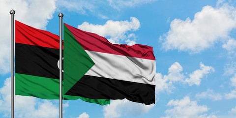 Libya and Sudan flag waving in the wind against white cloudy blue sky together. Diplomacy concept, international relations.