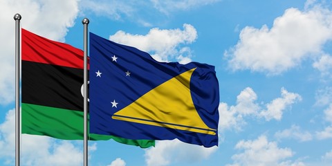 Libya and Tokelau flag waving in the wind against white cloudy blue sky together. Diplomacy concept, international relations.
