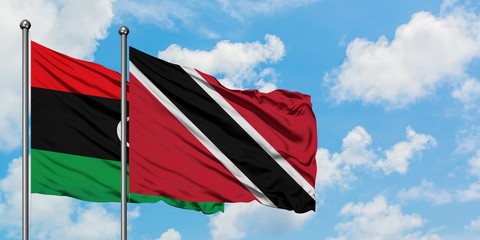 Libya and Trinidad And Tobago flag waving in the wind against white cloudy blue sky together. Diplomacy concept, international relations.