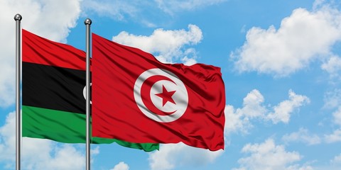 Libya and Tunisia flag waving in the wind against white cloudy blue sky together. Diplomacy concept, international relations.