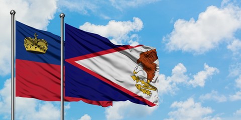 Liechtenstein and American Samoa flag waving in the wind against white cloudy blue sky together....