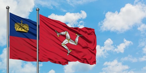 Liechtenstein and Isle Of Man flag waving in the wind against white cloudy blue sky together. Diplomacy concept, international relations.