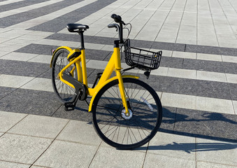 Fototapeta na wymiar Yellow bike with parking at the bike rack on stone street