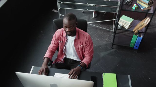 Confident black business guy typing keyboard on computer doing simple clicks finishing his work in the office walking away.