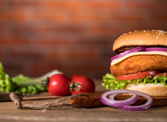 Fresh burger on wooden table and brick wall background