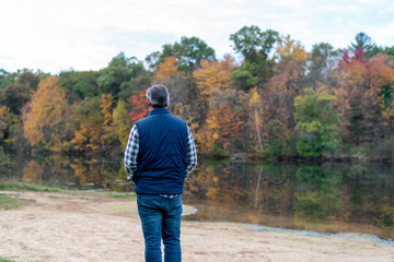 Middle age man enjoying fall colors by the lake in autumn
