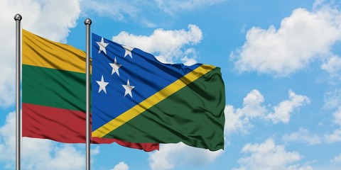 Lithuania and Solomon Islands flag waving in the wind against white cloudy blue sky together. Diplomacy concept, international relations.