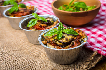 Original Italian eggplant Melanzane alla parmigiana in baking dish on the wooden table.
