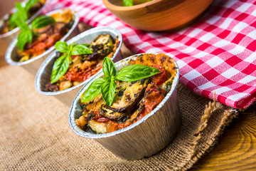 Original Italian eggplant Melanzane alla parmigiana in baking dish on the wooden table.