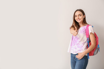 Beautiful female student showing thumb-up on white background
