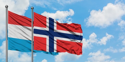 Luxembourg and Bouvet Islands flag waving in the wind against white cloudy blue sky together. Diplomacy concept, international relations.