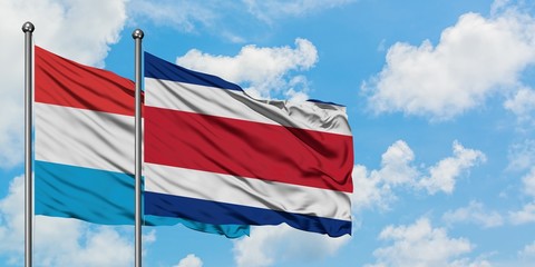 Luxembourg and Costa Rica flag waving in the wind against white cloudy blue sky together. Diplomacy concept, international relations.