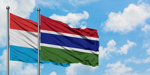 Luxembourg and Gambia flag waving in the wind against white cloudy blue sky together. Diplomacy concept, international relations.