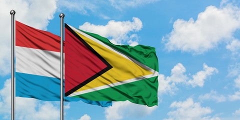Luxembourg and Guyana flag waving in the wind against white cloudy blue sky together. Diplomacy concept, international relations.