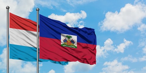 Luxembourg and Haiti flag waving in the wind against white cloudy blue sky together. Diplomacy concept, international relations.