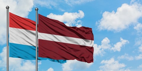 Luxembourg and Latvia flag waving in the wind against white cloudy blue sky together. Diplomacy concept, international relations.