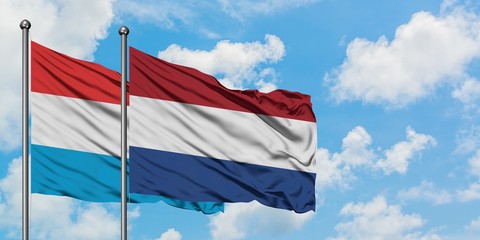 Luxembourg and Netherlands flag waving in the wind against white cloudy blue sky together. Diplomacy concept, international relations.
