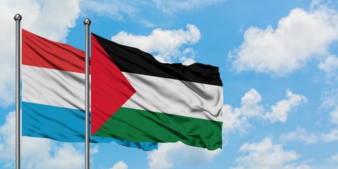 Luxembourg and Palestine flag waving in the wind against white cloudy blue sky together. Diplomacy concept, international relations.