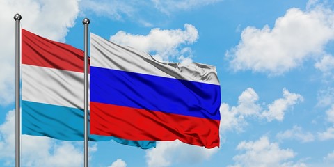 Luxembourg and Russia flag waving in the wind against white cloudy blue sky together. Diplomacy concept, international relations.